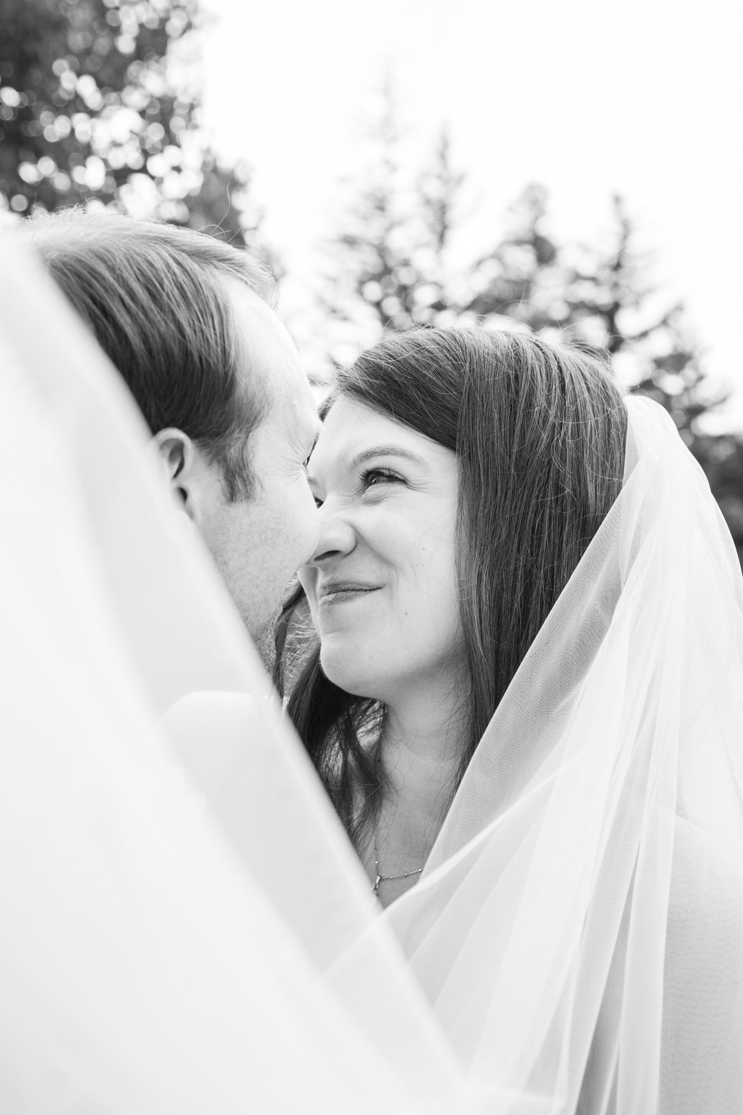 A black and white photo shows a bride in a white veil during a tender wedding moment from wedding at The Westin Riverfront in Avon CO