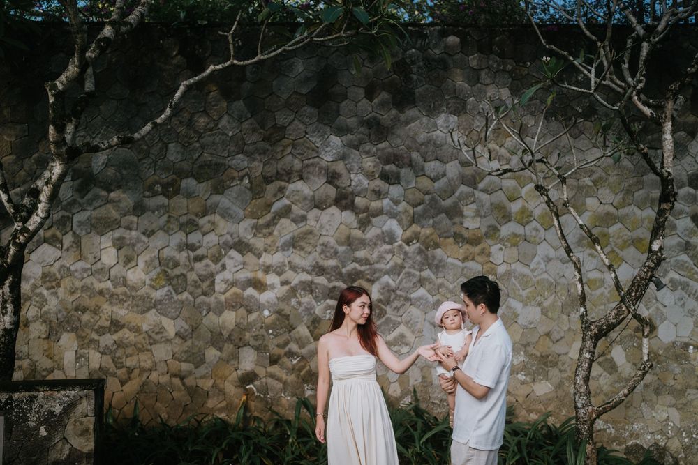 A couple in white outfits walking together in a rustic stone-walled setting.