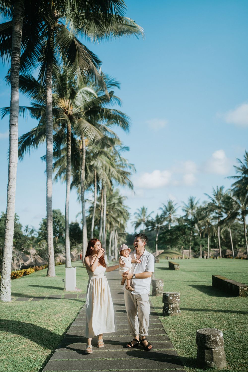 A couple strolling down a scenic palm-lined pathway on a sunny day.