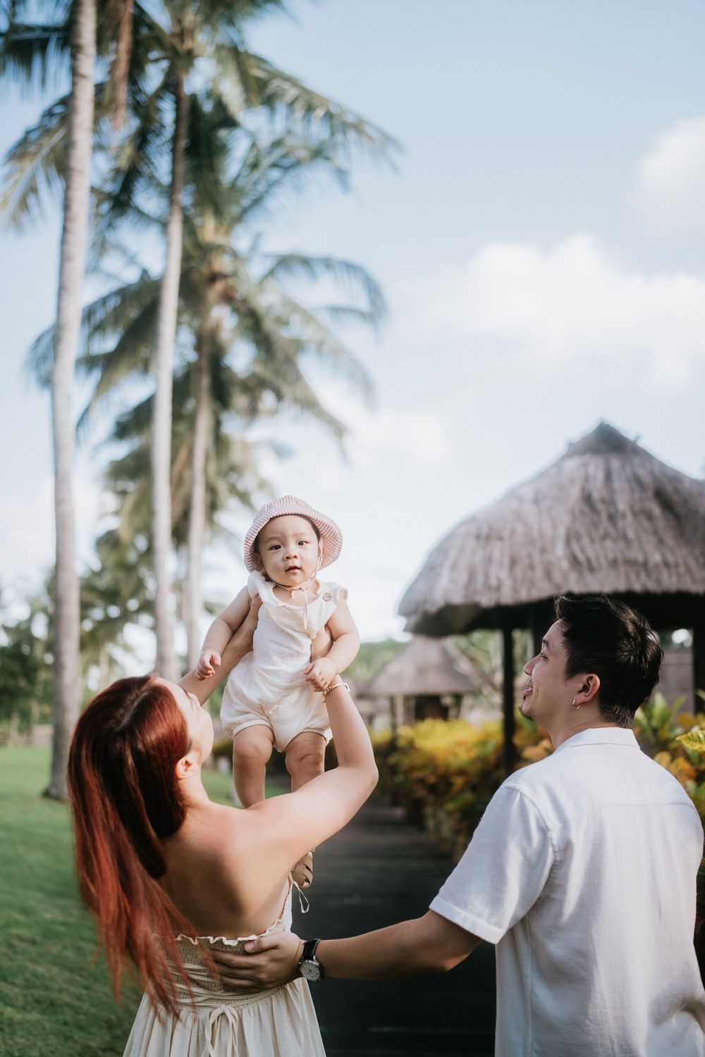 A family sharing joyful moments together under palm trees at a tropical resort.