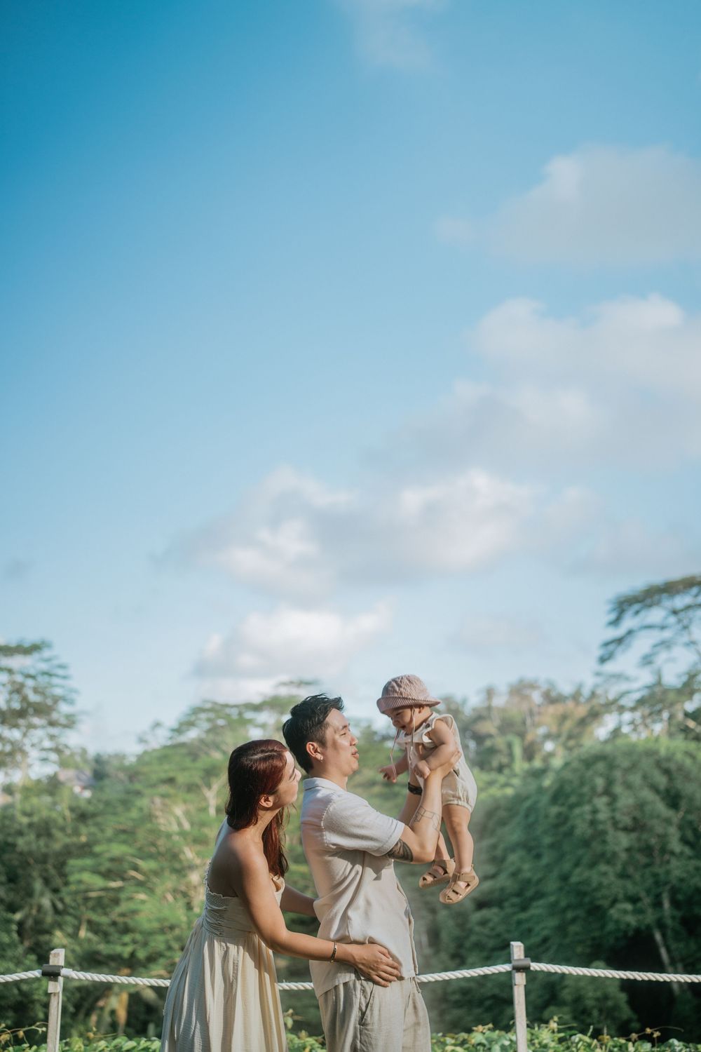 A family sharing playful moments on a tropical deck with blue skies overhead.