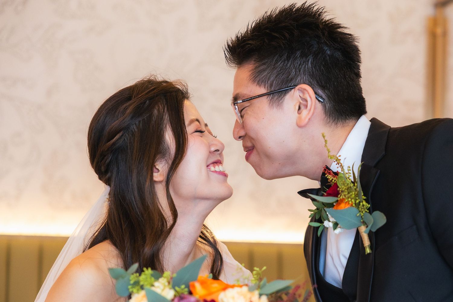 A happy couple share a close intimate moment together at their wedding, with the groom wearing a boutonniere.