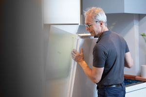 Person checking mobile phone while standing in bright modern interior space.