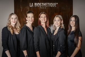 Professional hairstyle team wearing black uniforms poses together in treatment room with La Biosthetique branding.