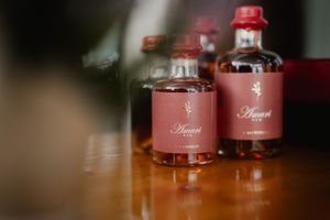 Two pink glass bottles with red caps sitting on a wooden surface in soft focus lighting.