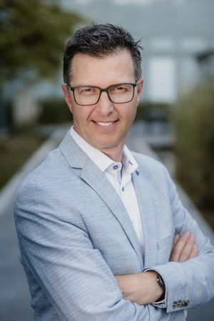 Professional portrait session showing different poses in a light gray suit against an outdoor background.