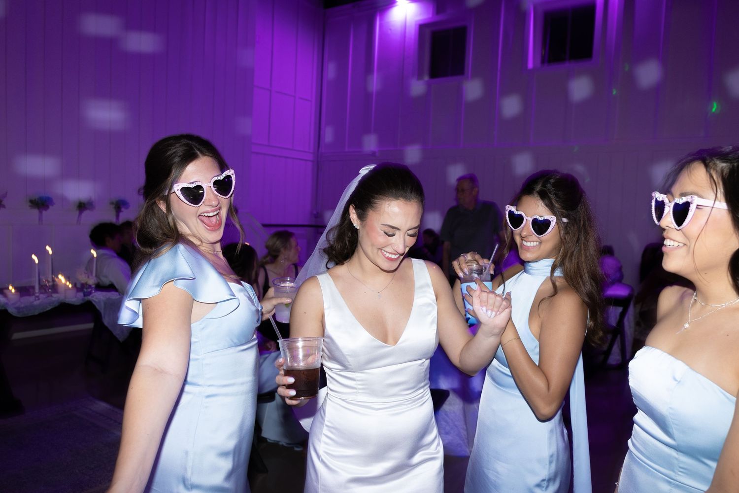 Group of people dancing and socializing at a nightclub with purple lighting and party atmosphere.