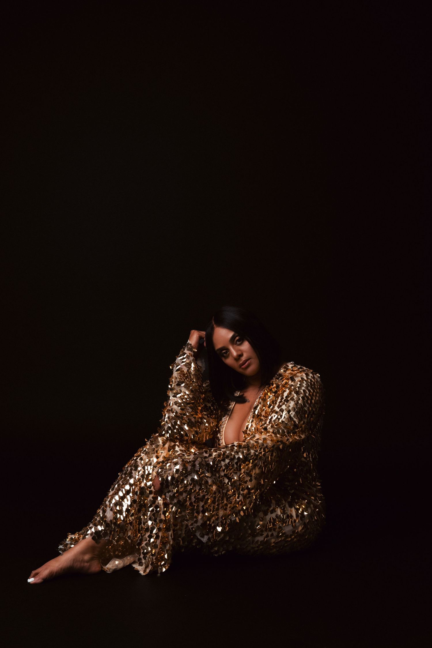 Artistic set of five sequential photos showing a figure draped in sparkly golden fabric against a dark background.