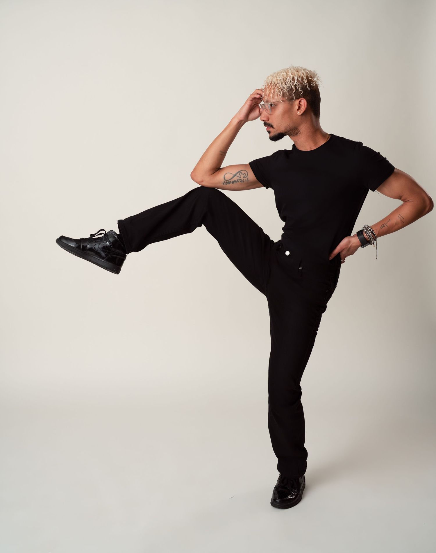 Modern dancer in black attire performs a striking balancing pose during studio session.