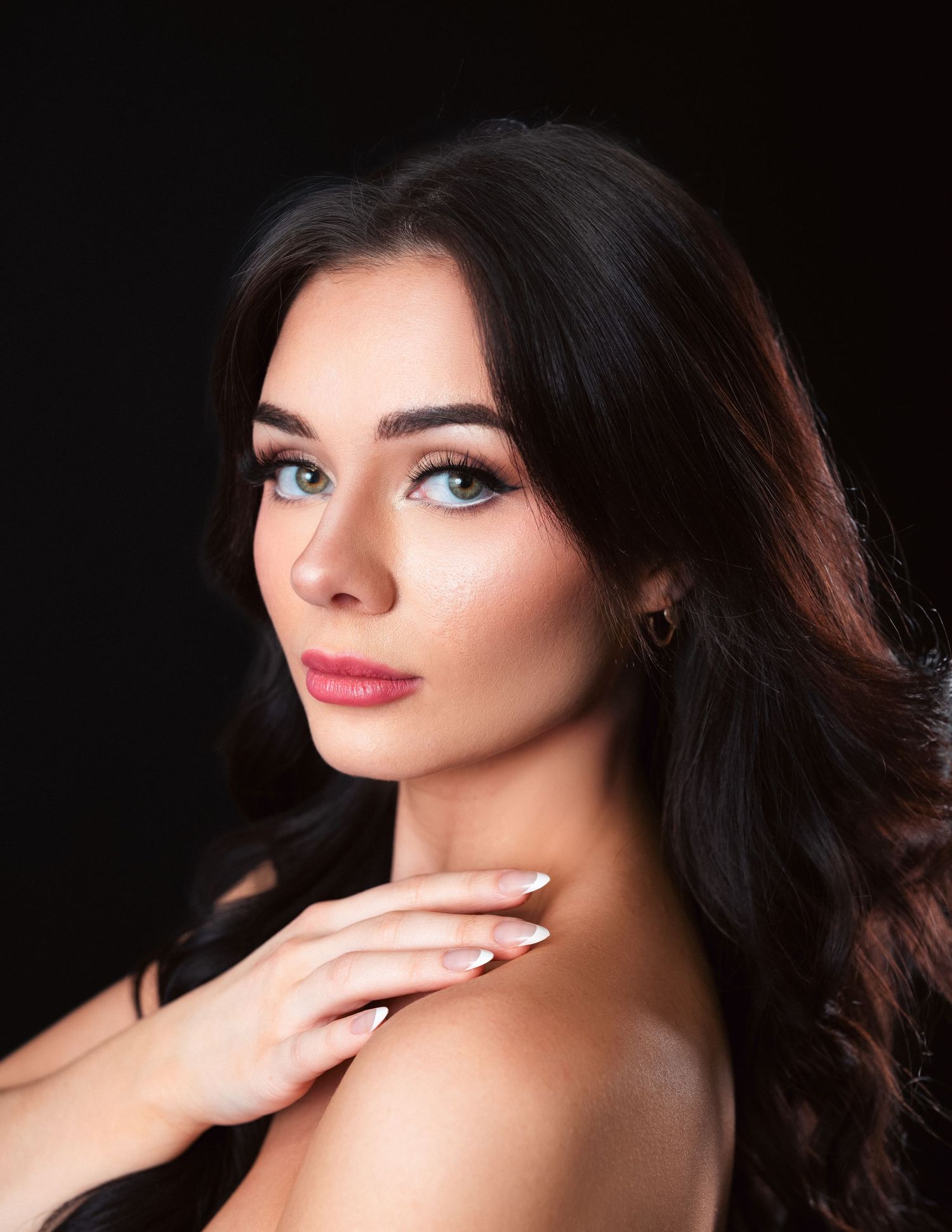 Professional glamour photography portraits against dark background showing dramatic makeup and flowing dark hair.