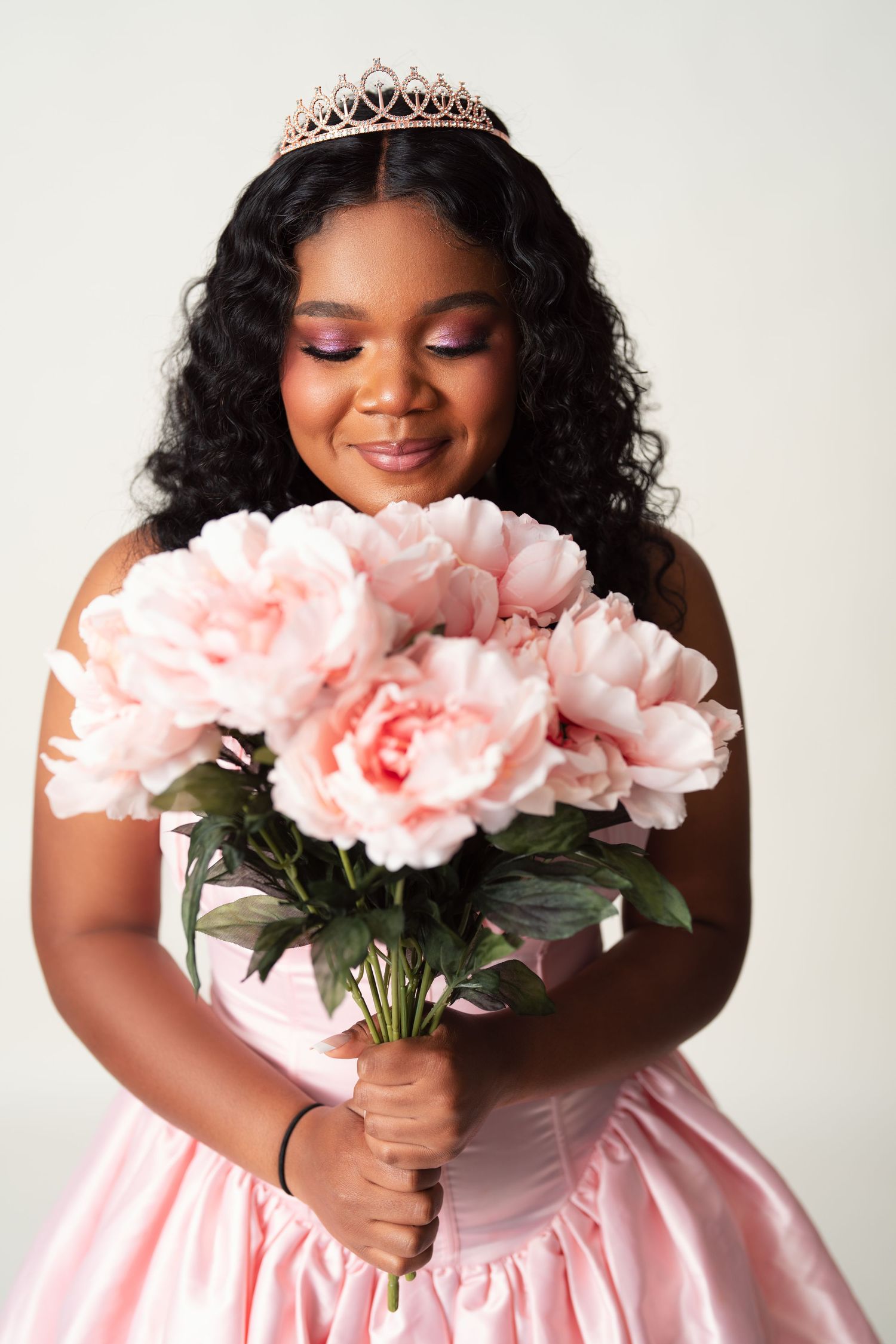 Four photos show a person in a pink gown and tiara holding a bouquet of pink roses while posing gracefully.
