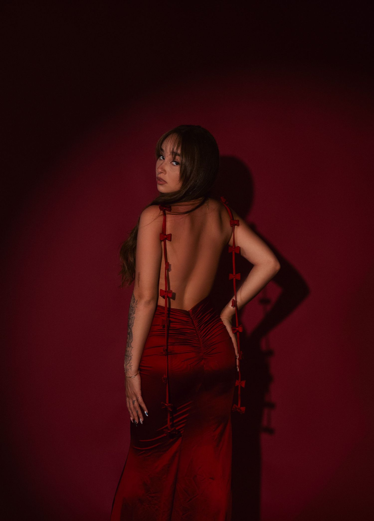 A figure in a flowing red dress poses dramatically against a dark background in a series of artistic portraits.