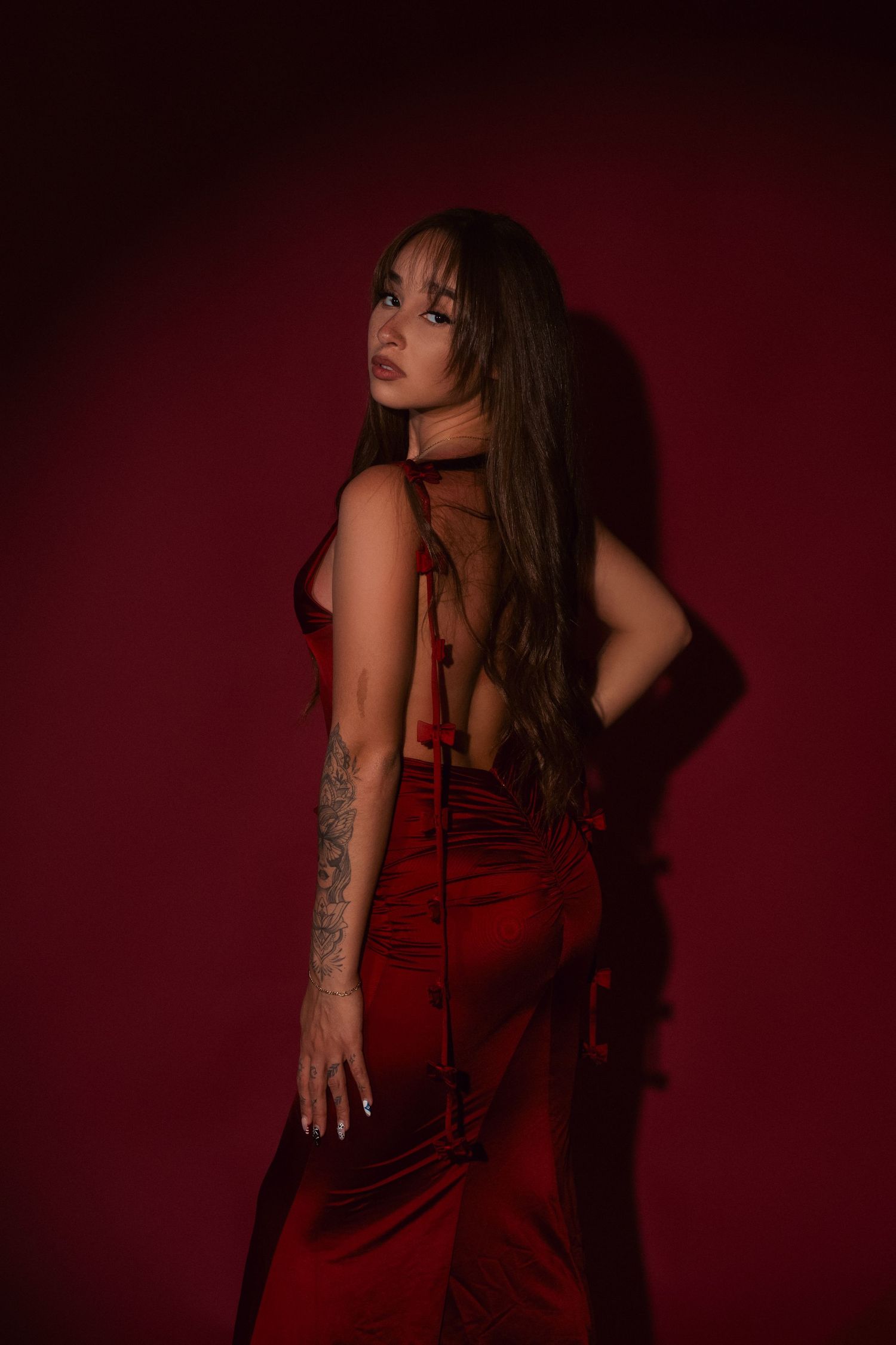 Moody boudoir photography series with dramatic poses against deep red backdrop showing artistic silhouettes.