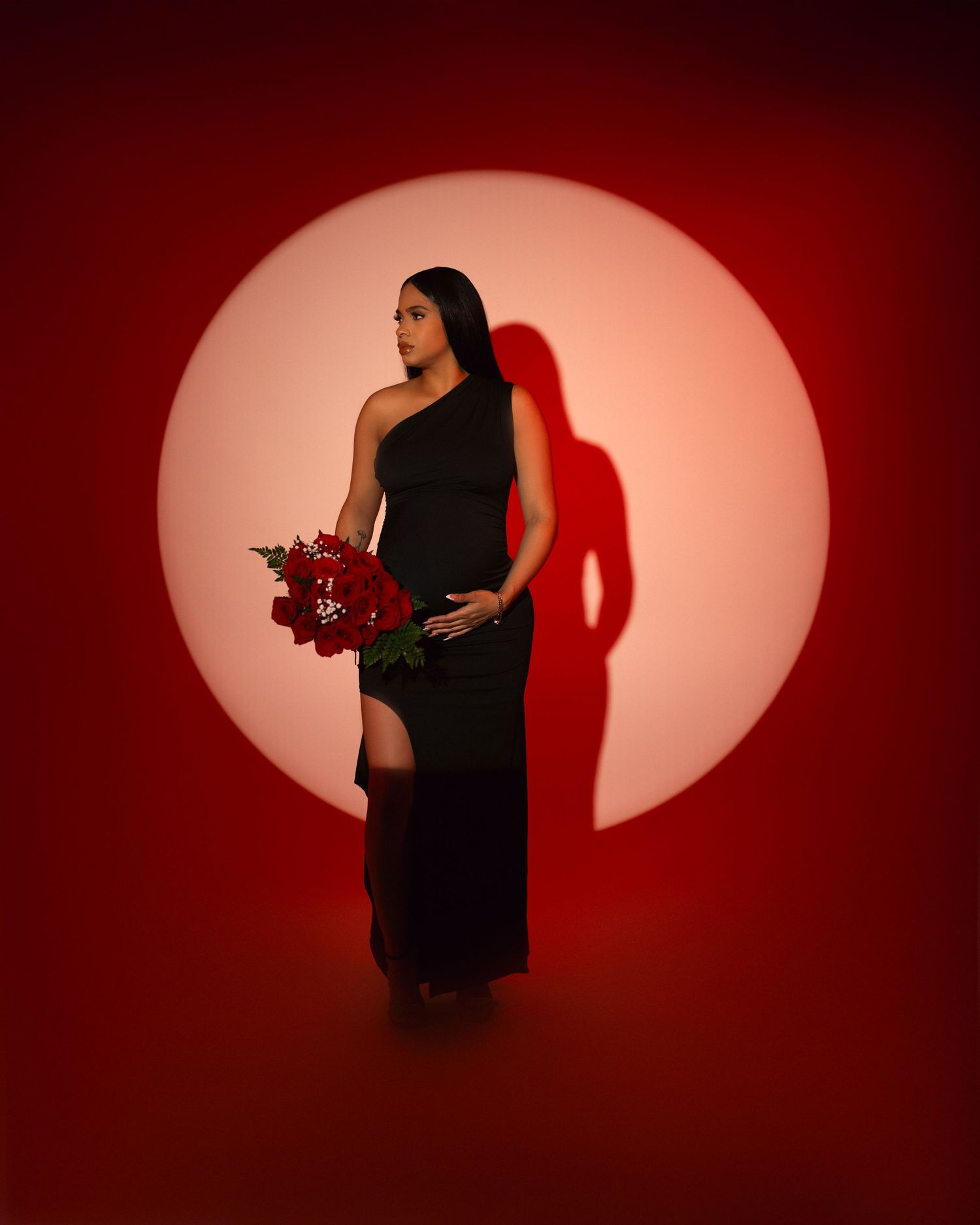 Silhouetted figure in black dress against dramatic red oval lighting performs sequence of dynamic dance movements.