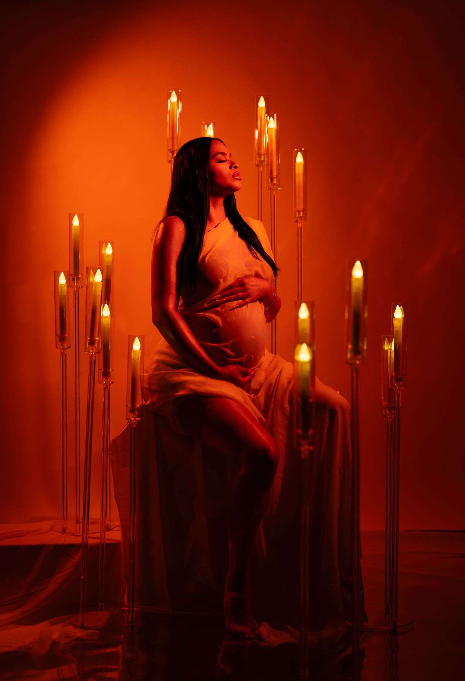 A moody candlelit scene in warm red tones shows a dramatic figure silhouetted against glowing candle flames.