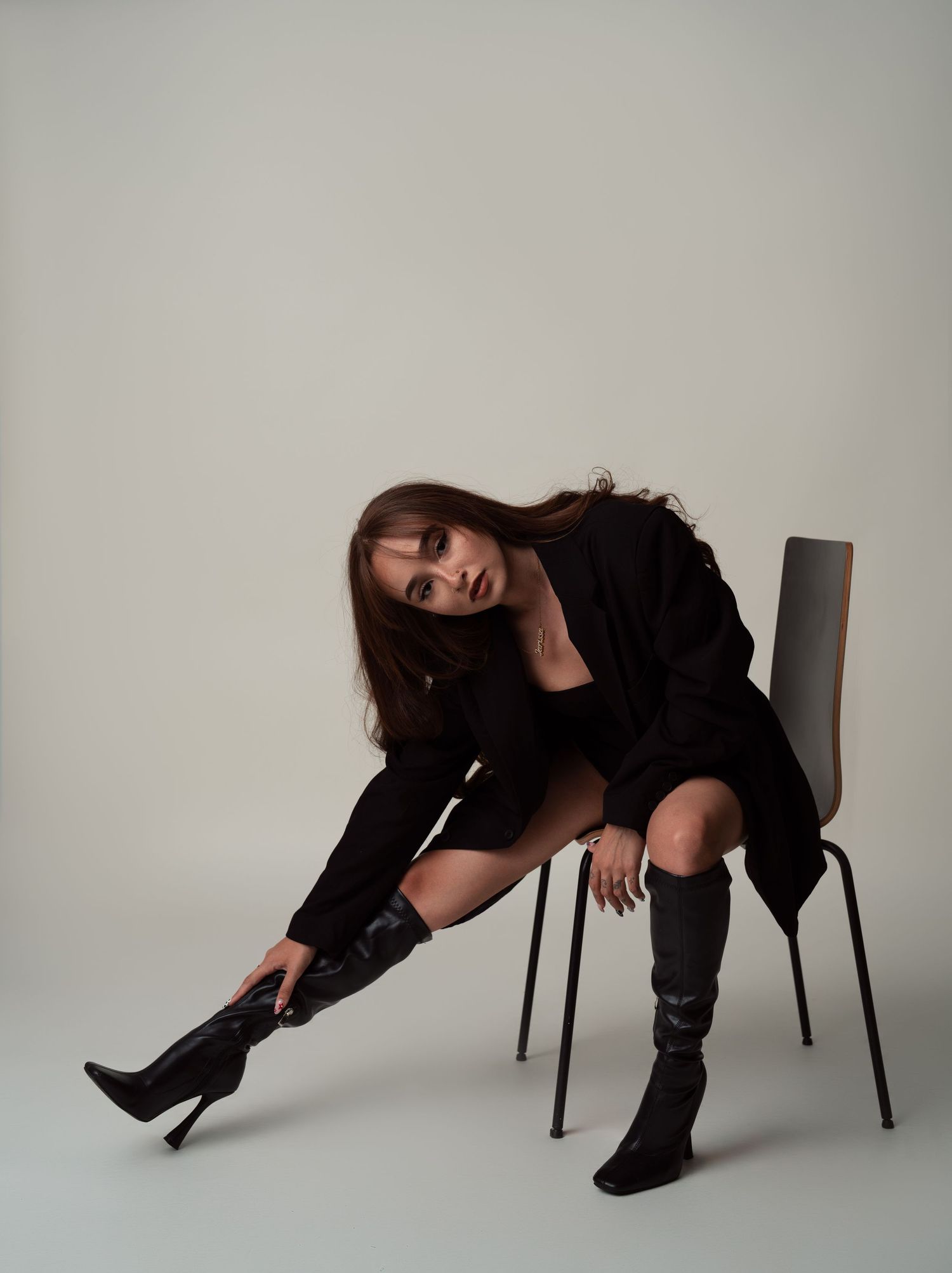 Fashion shoot sequence showing dynamic poses with black chair against minimalist studio background.