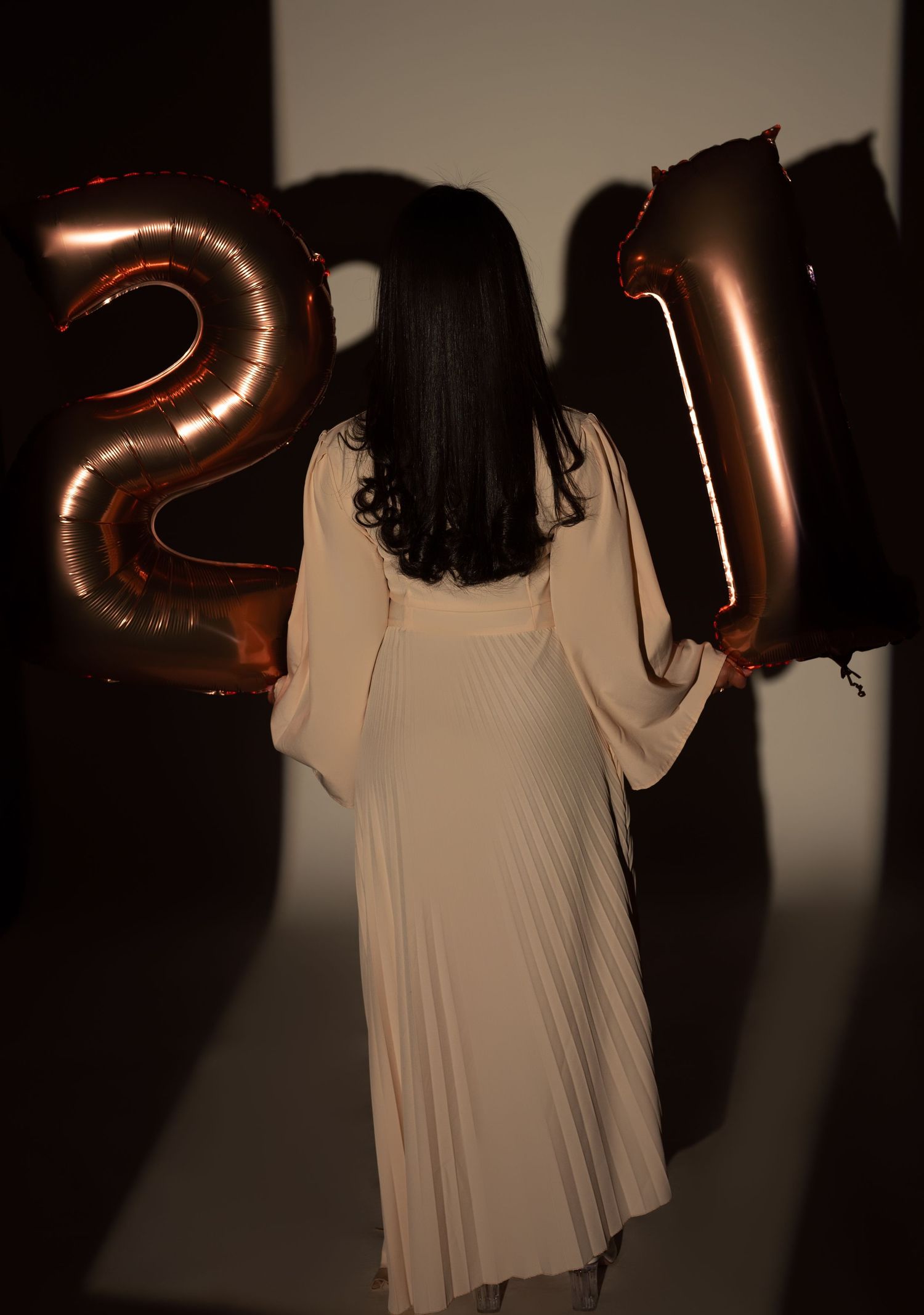 A sequence showing silhouetted hands holding shiny metallic balloon numbers against a dark background.