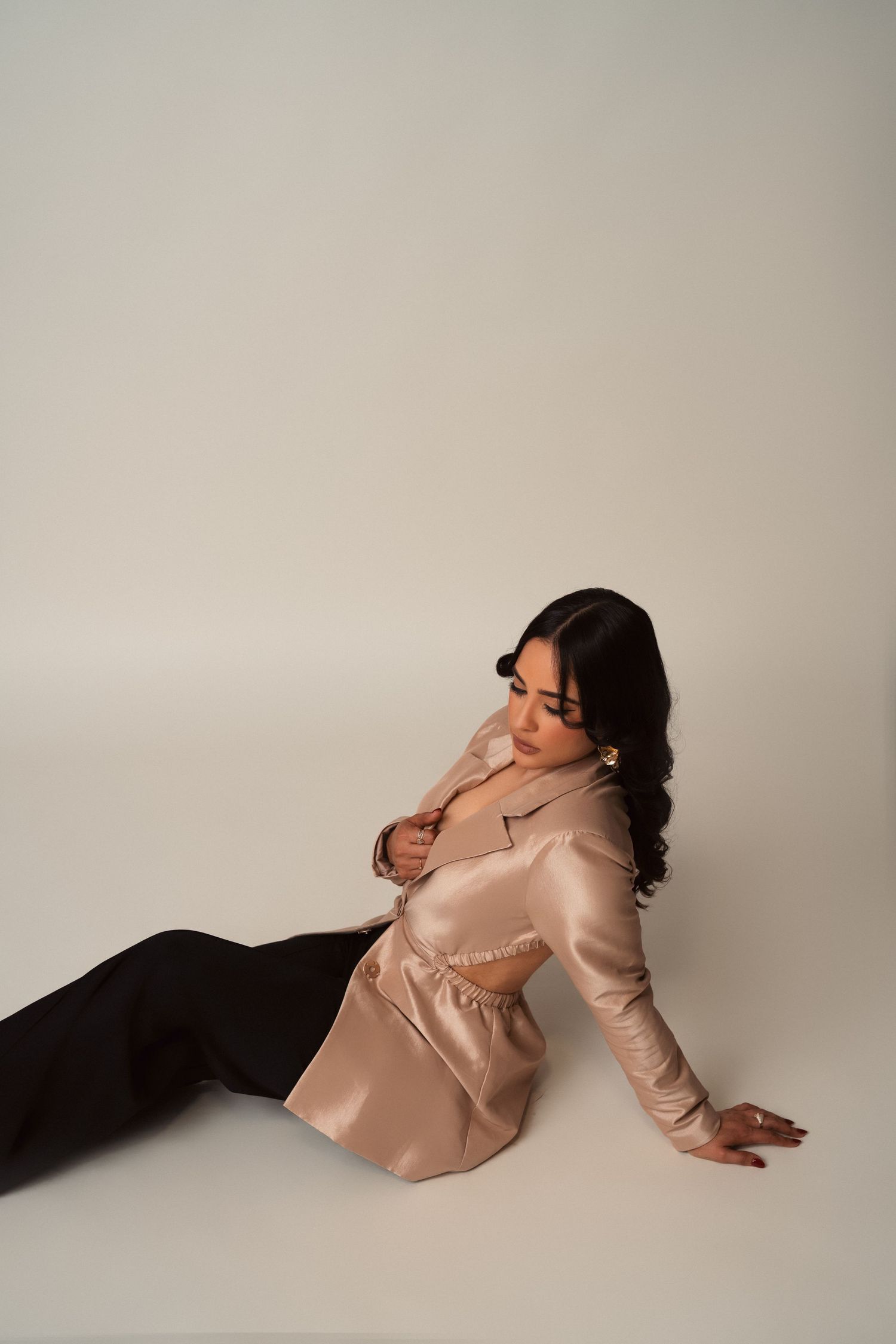 Artistic photo series of a person in light pink blazer lounging against white backdrop in dramatic poses.
