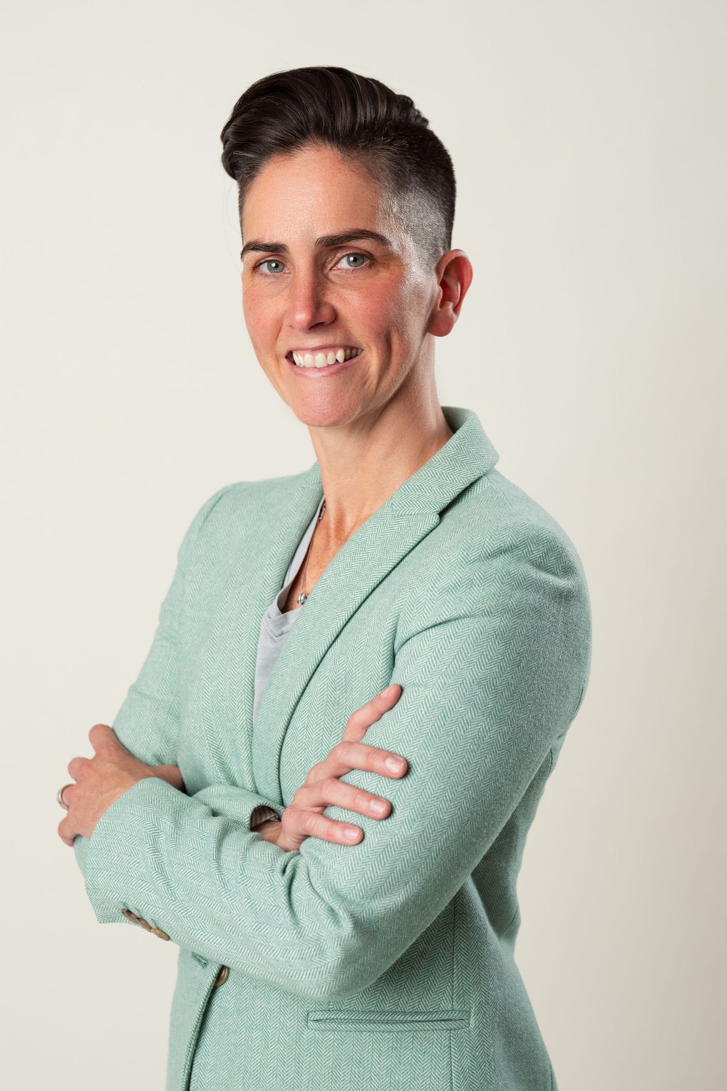 Professional portrait of someone in a mint green blazer with a confident pose against a light background.
