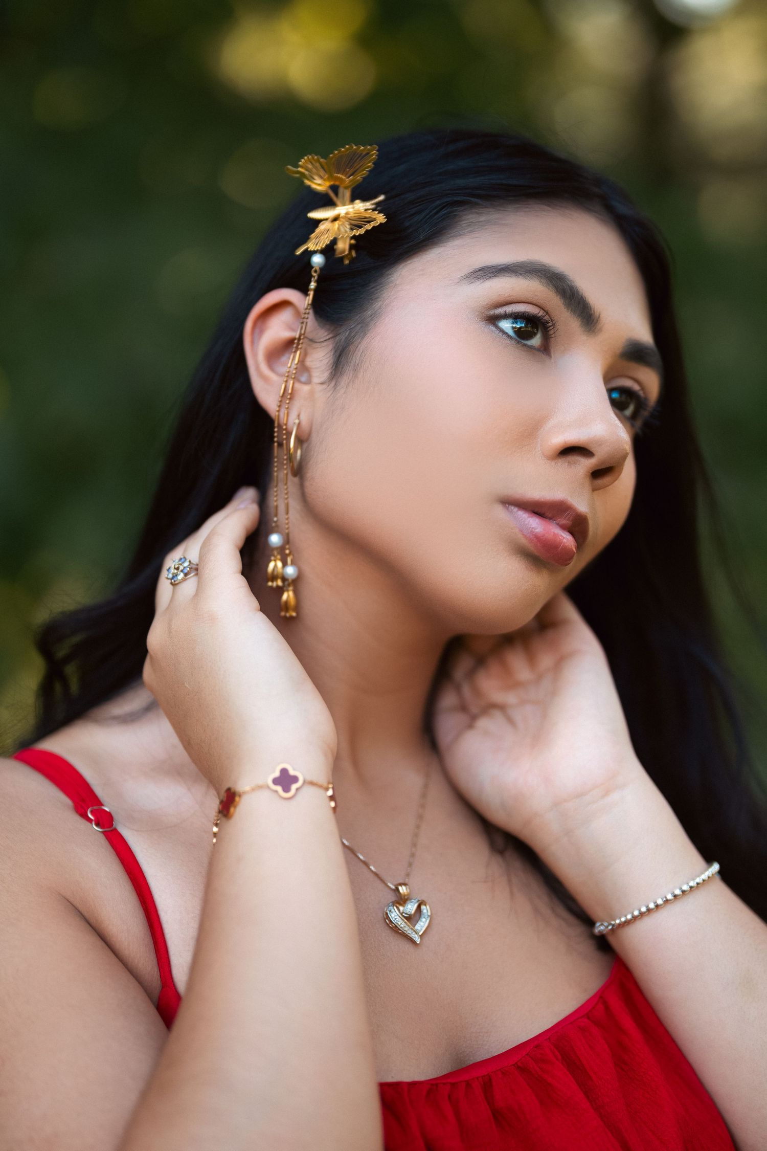 Close-up fashion portraits of a model in red dress wearing gold butterfly jewelry and accessories in an outdoor setting.