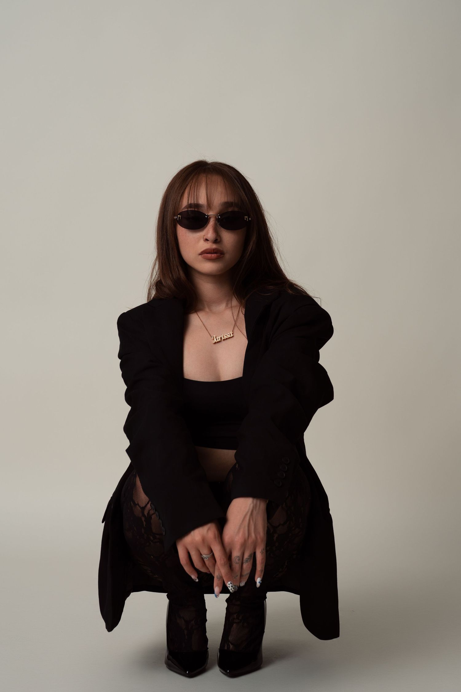 Figure in black attire poses in a moody fashion shoot series with stark lighting and monochromatic styling.
