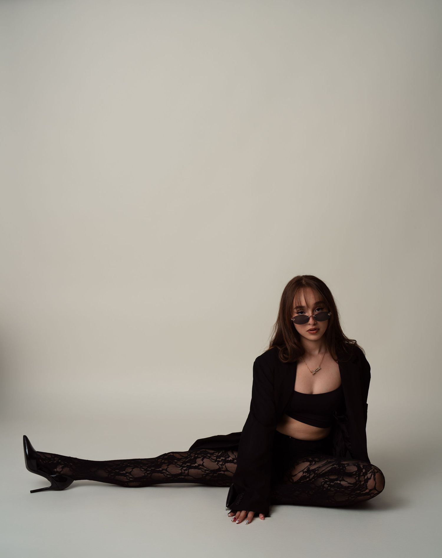 Art series showing person lying down in black lace dress against plain background captured in minimalist style.