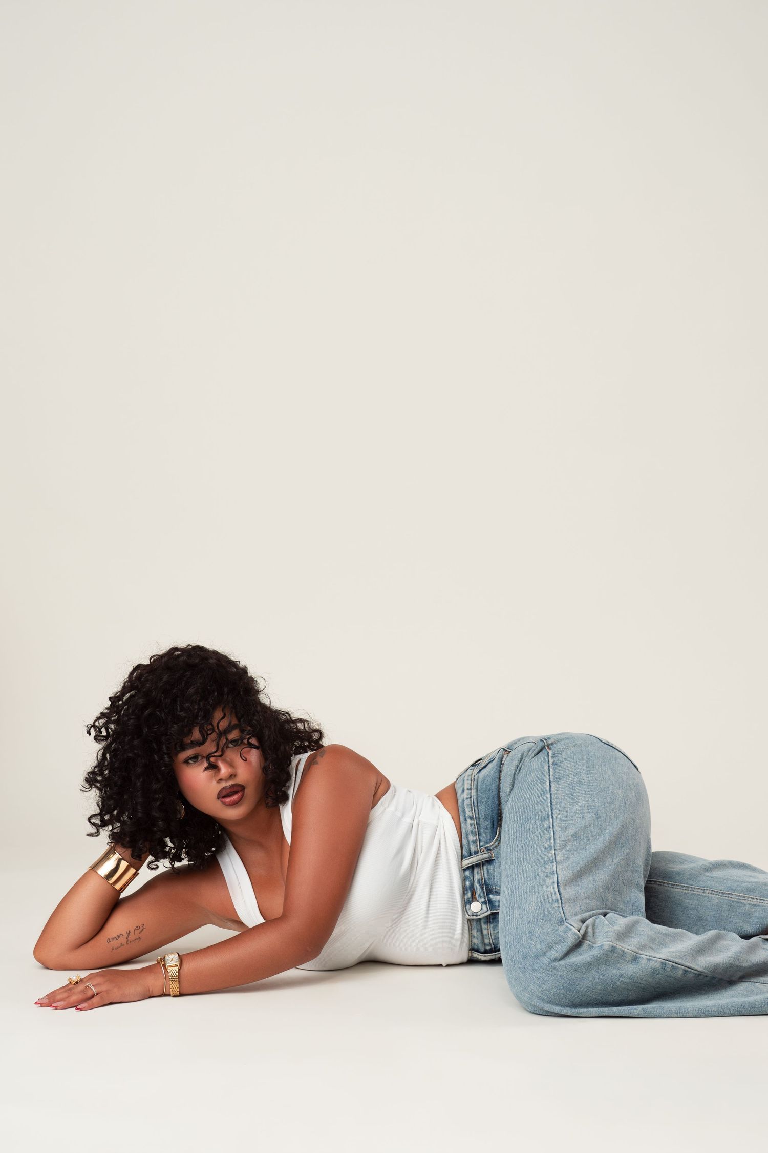 Person wearing blue jeans and white top lying down on clean white background in three connected poses.