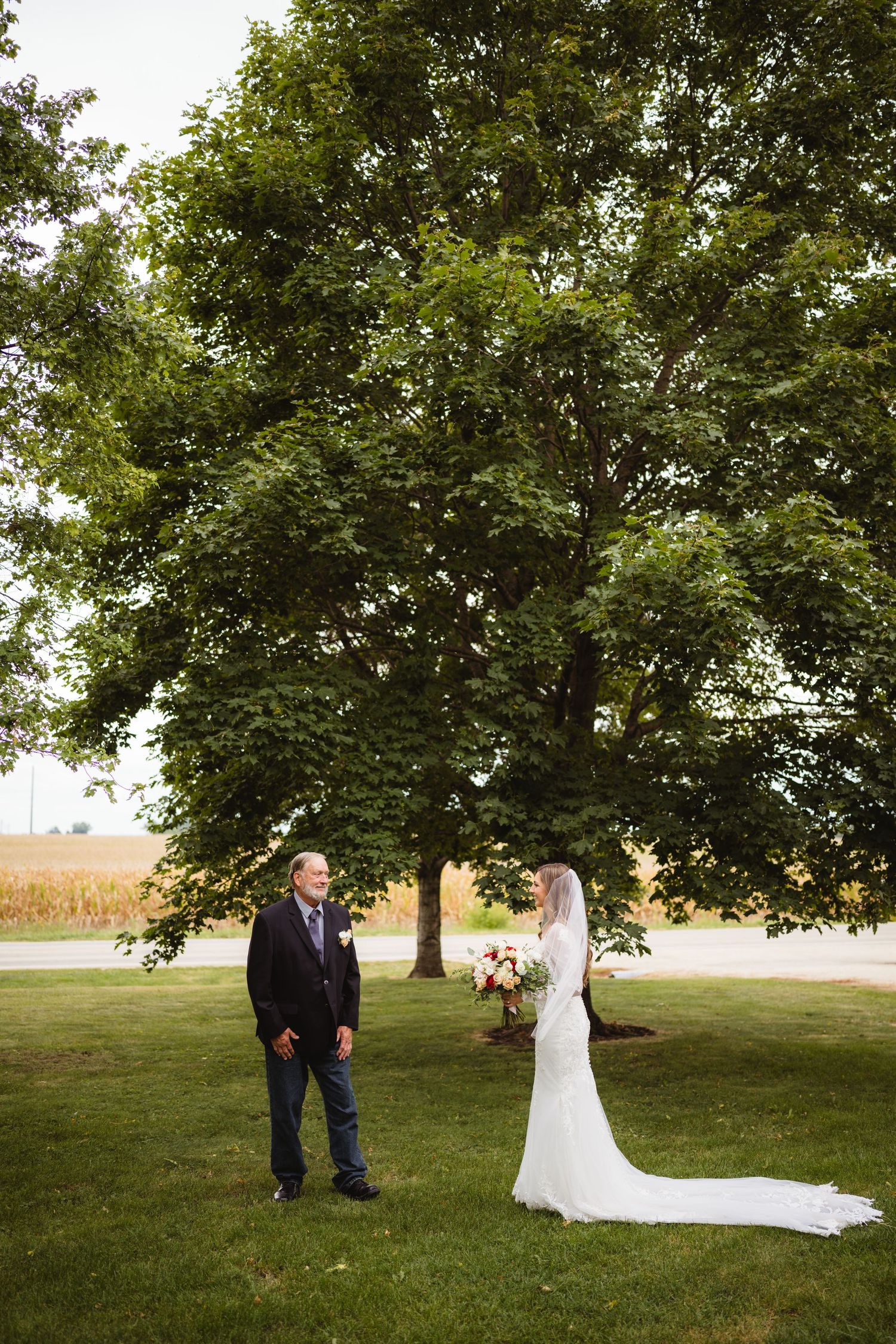 A couple stands on a grassy hill during their first look moment at a rustic outdoor wedding ceremony.