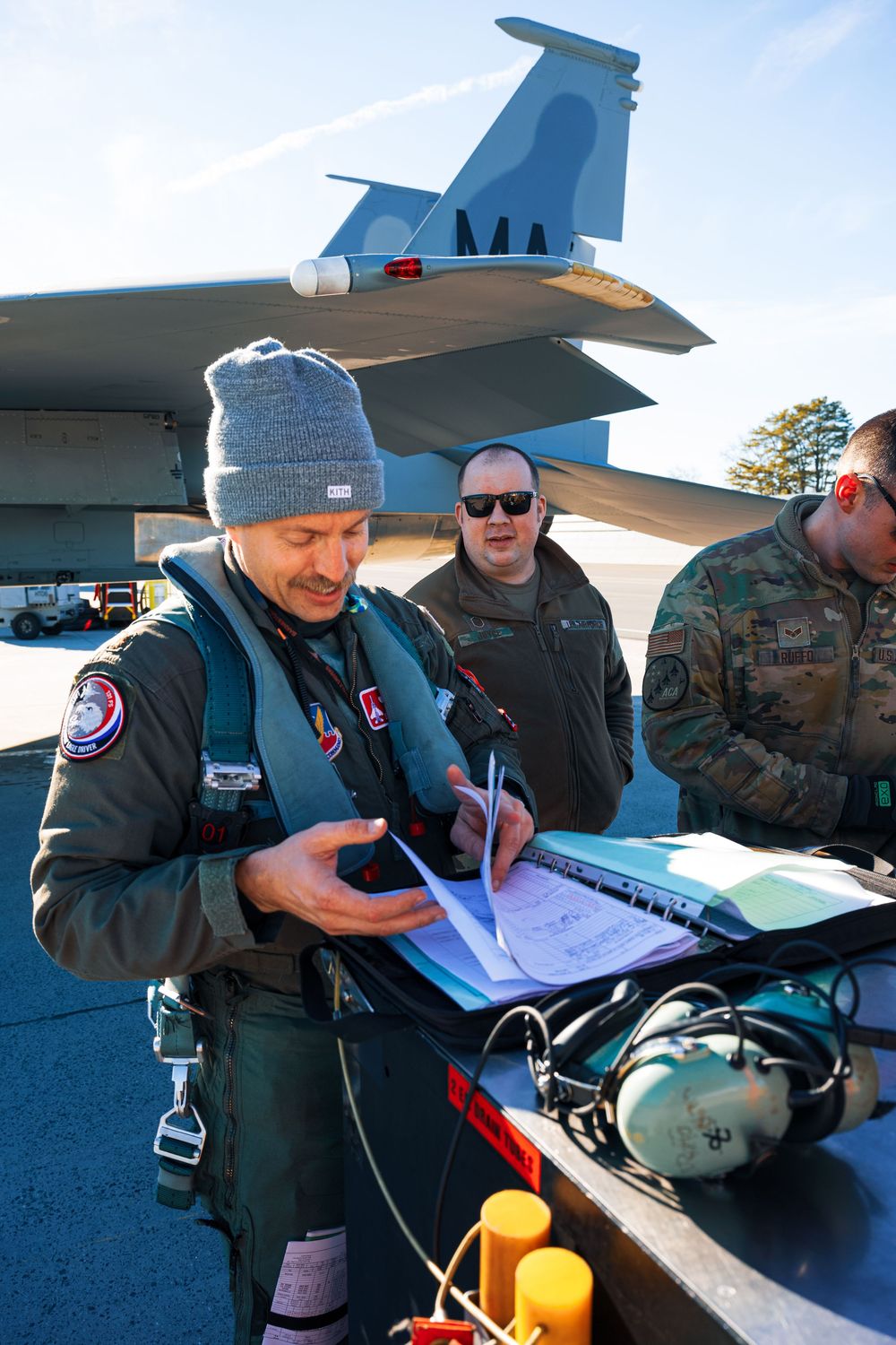 Personnel performing maintenance checks and paperwork near a parked aircraft.
