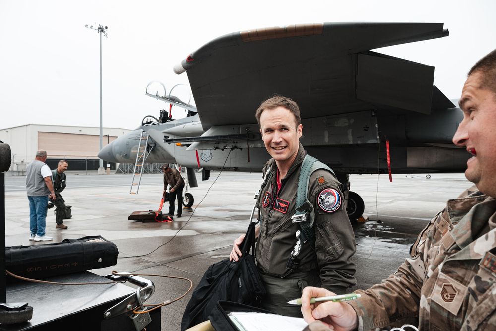 Military personnel gathered around aircraft on tarmac during training exercise.