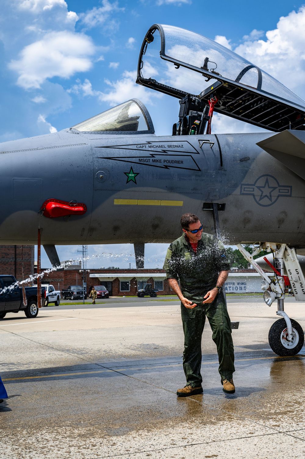Military personnel cleaning and maintaining aircraft on sunny tarmac.