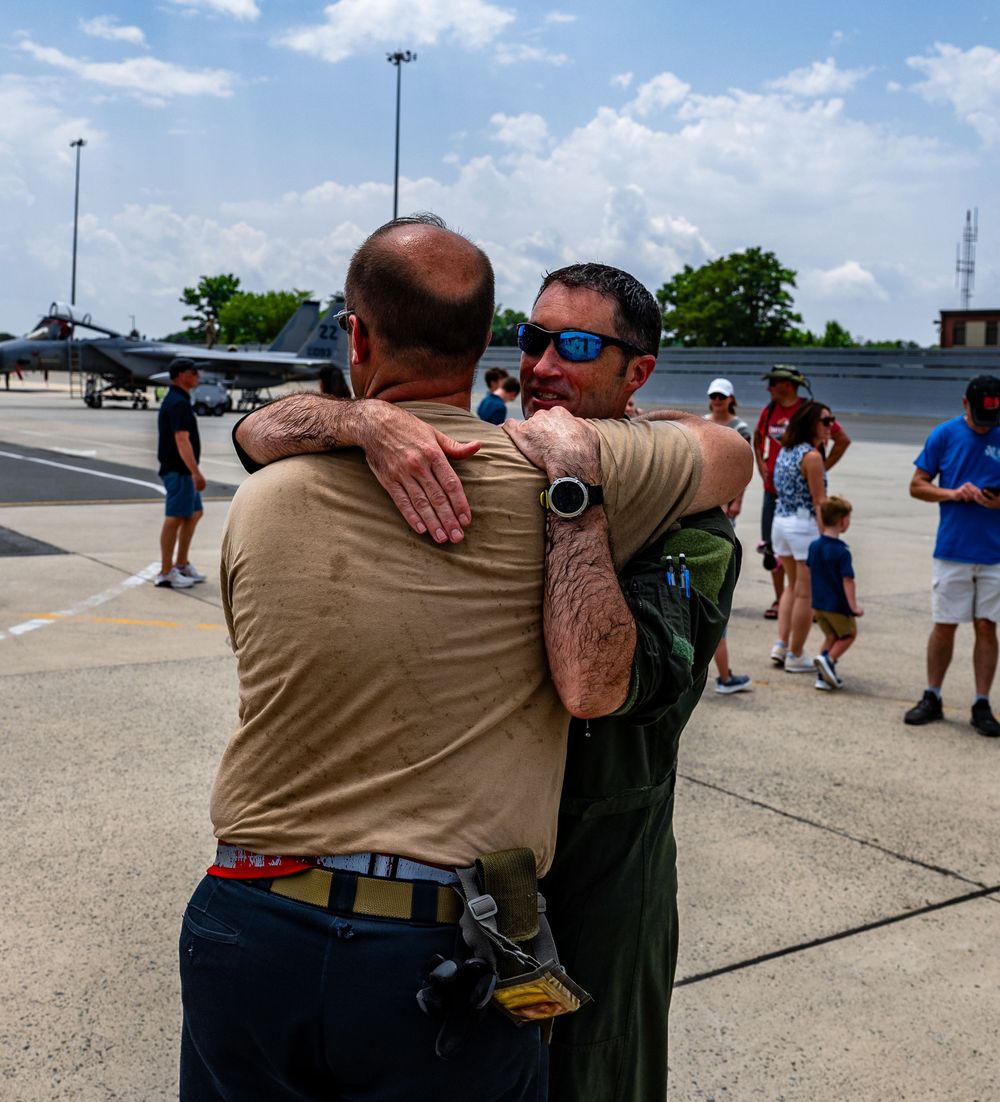 Two people sharing an emotional embrace on an airfield tarmac.