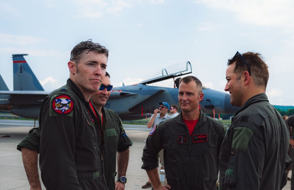 Military personnel gathered on airfield tarmac during daytime operations.