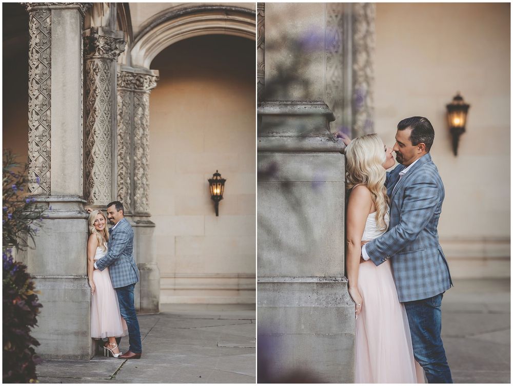 A couple in romantic poses share tender moments during a professional photo session against a light stone wall background.