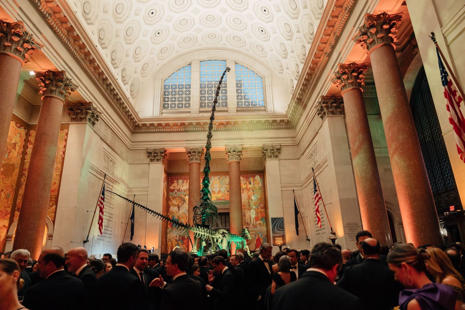 A panoramic view of an ornate ballroom interior with classical columns and decorative moldings illuminated in warm lighting.