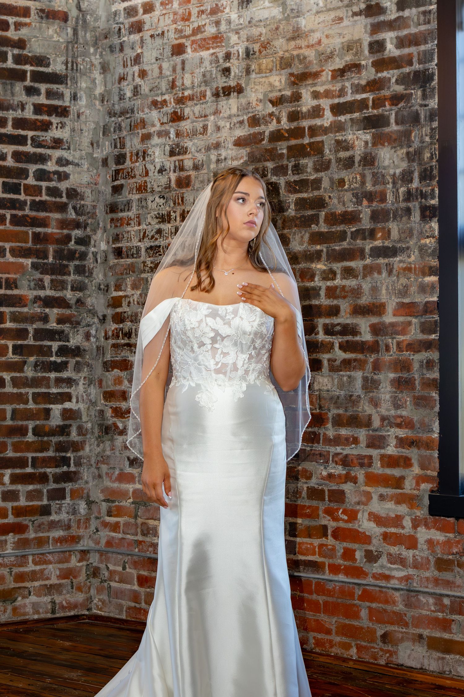 Classic wedding gown with fitted bodice photographed in historic brick venue with dramatic lighting.