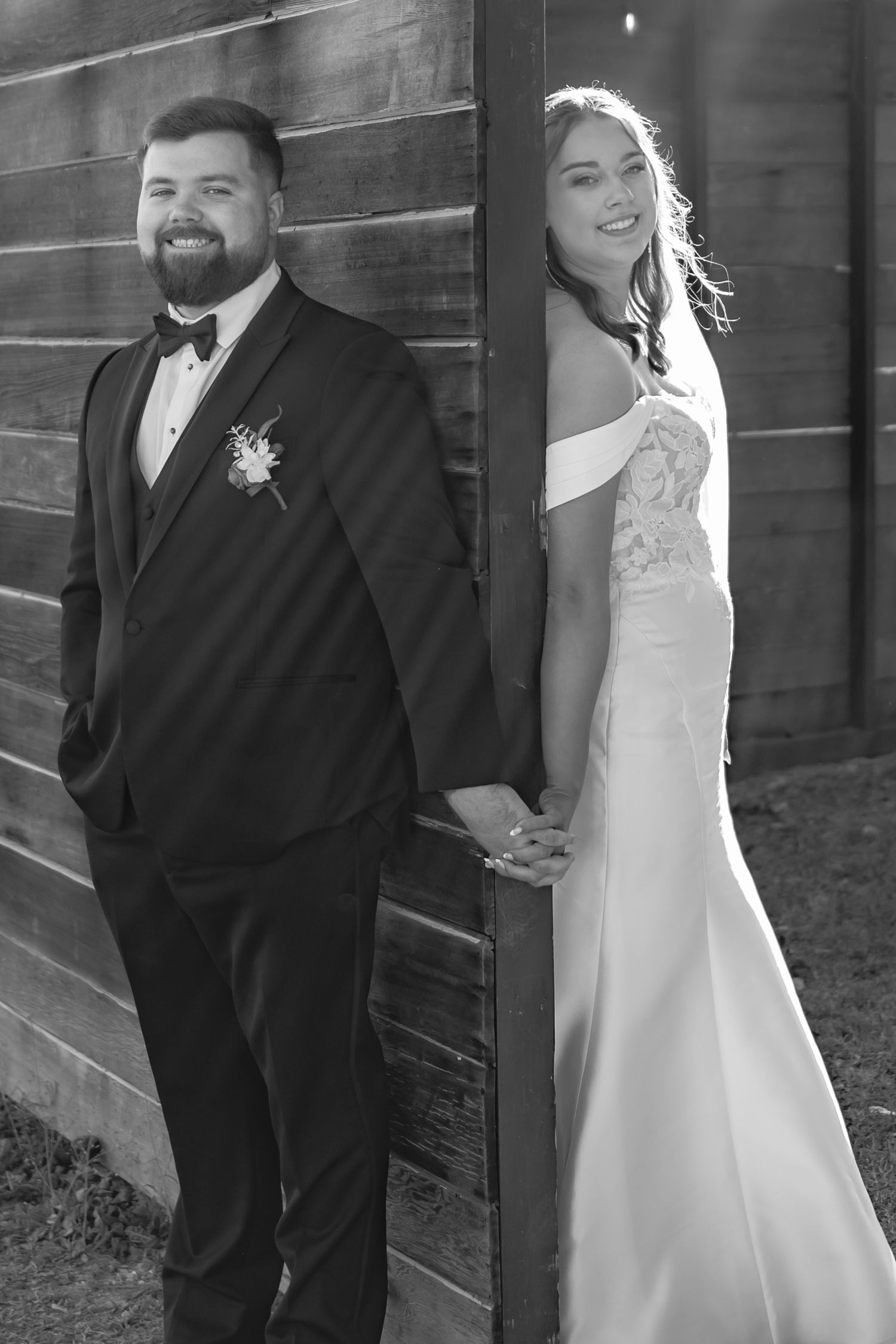 A wedding couple poses together against a rustic wooden wall in black and white photos.