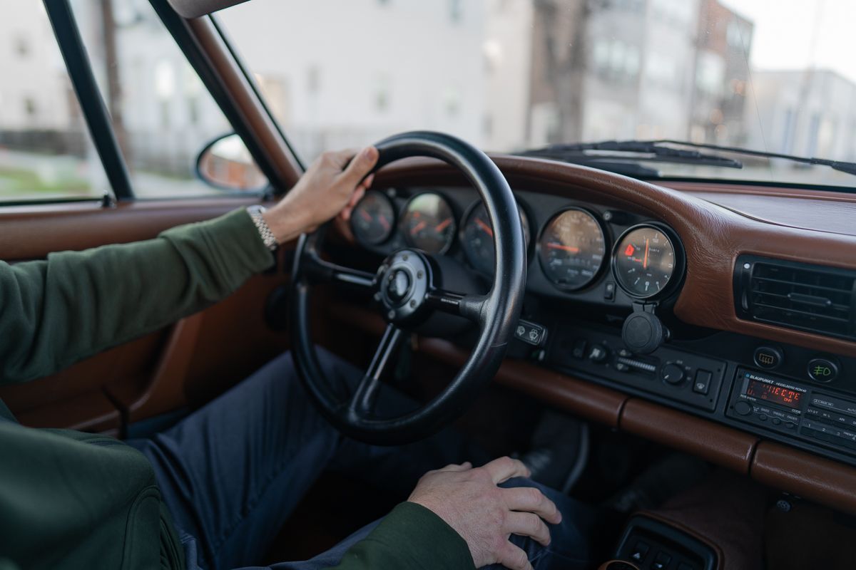 Interior view of a vintage car dashboard with hands on the steering wheel.