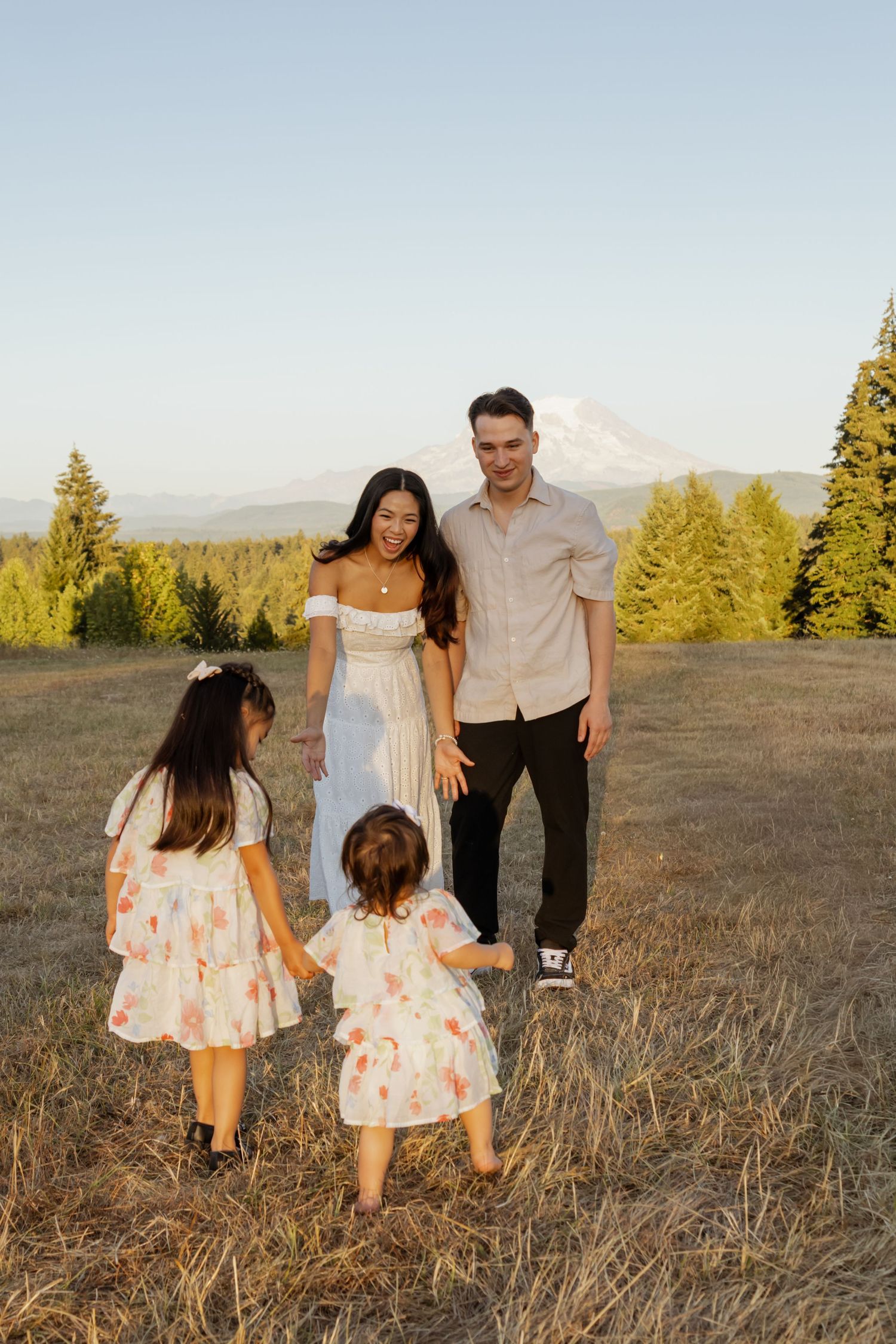 Family of six posing in an autumn meadow with evergreen trees, featuring a woman with bright red hair.