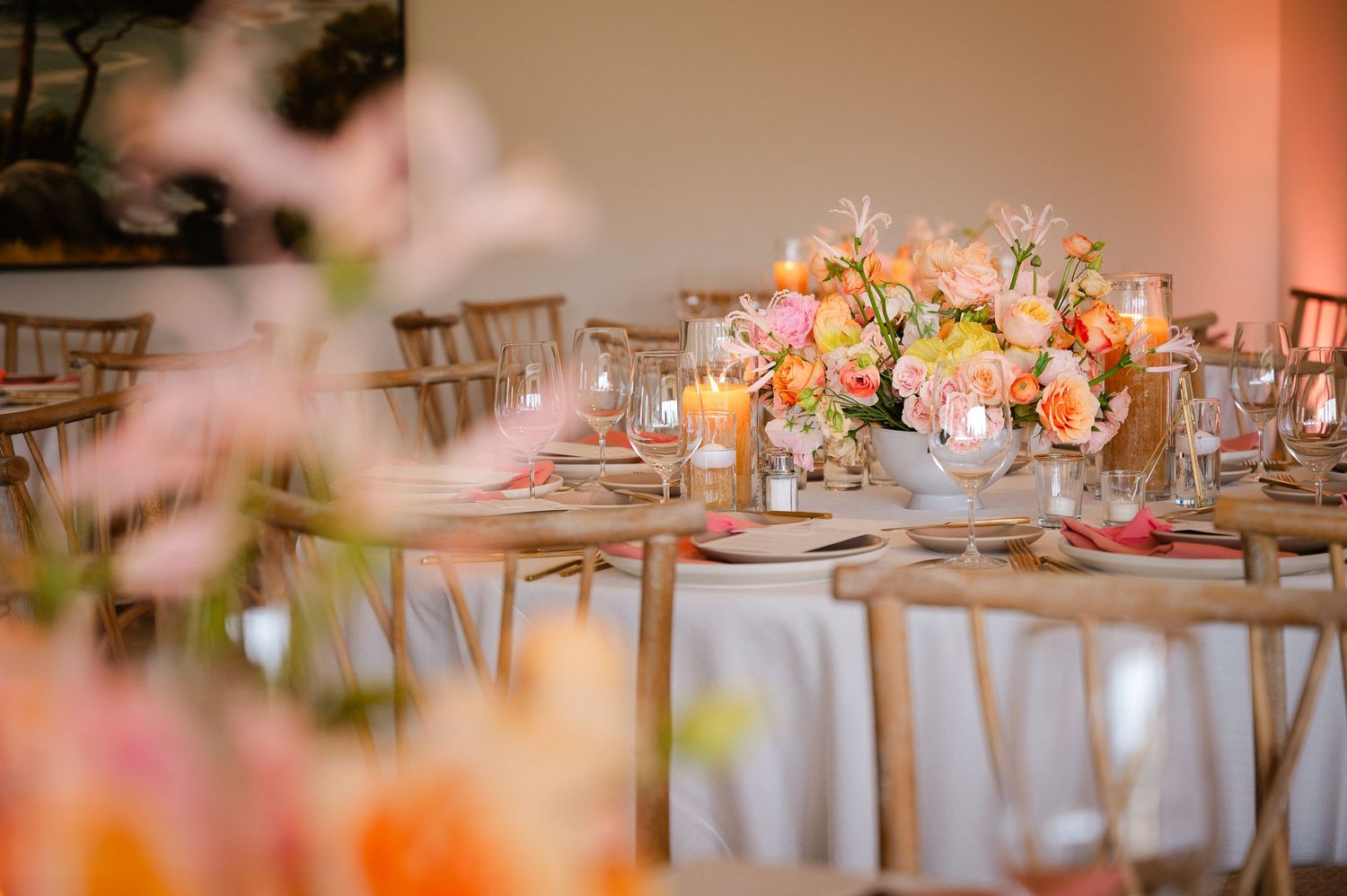 Elegant wedding reception tables decorated with pink and white floral centerpieces and soft candlelight in a romantic setting.