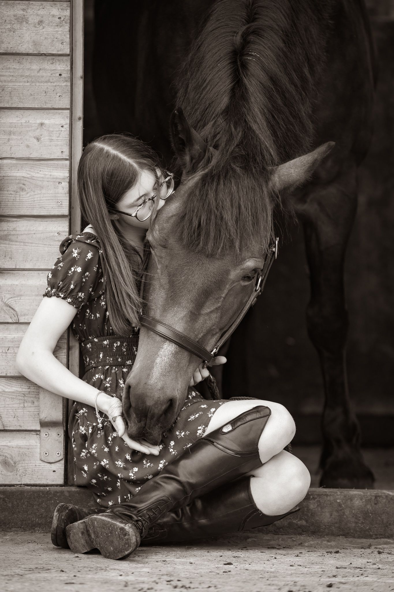 Young girl in denim overalls embraces a palomino horse in a sun-dappled forest setting.