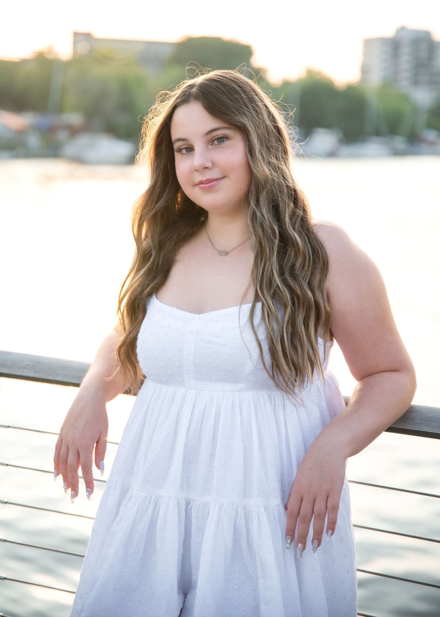 A series of five portraits showing the same woman in a white summer dress posing against an outdoor setting at sunset.