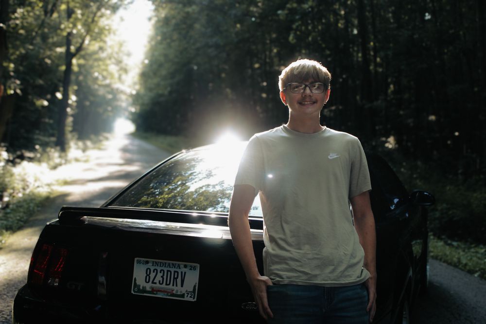 Blayden leaning on his car.
