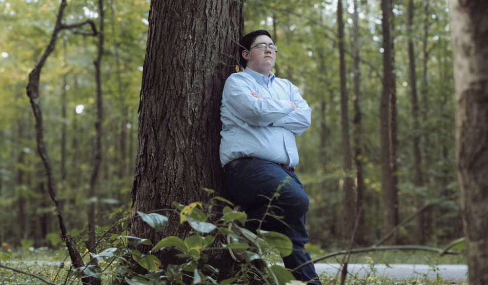 CJ leaning on a tree.