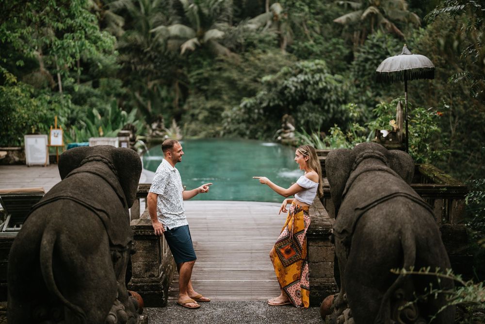 A couple explores a lush tropical garden path with stone walls and natural foliage.