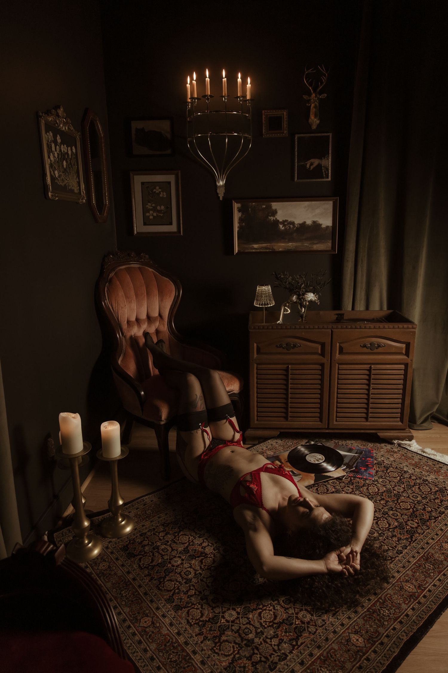 A dimly lit room with candles and vintage furniture creates a moody atmosphere on a patterned carpet.