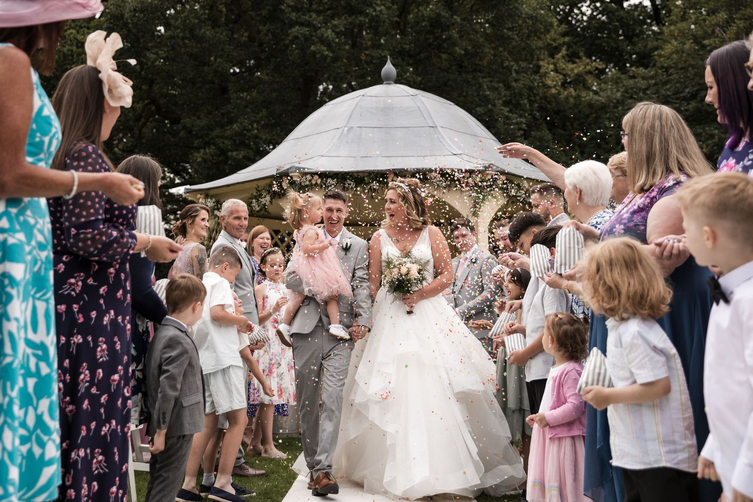 Bride & Groom are covered in confetti as they walk down the aisle after at Kelham House