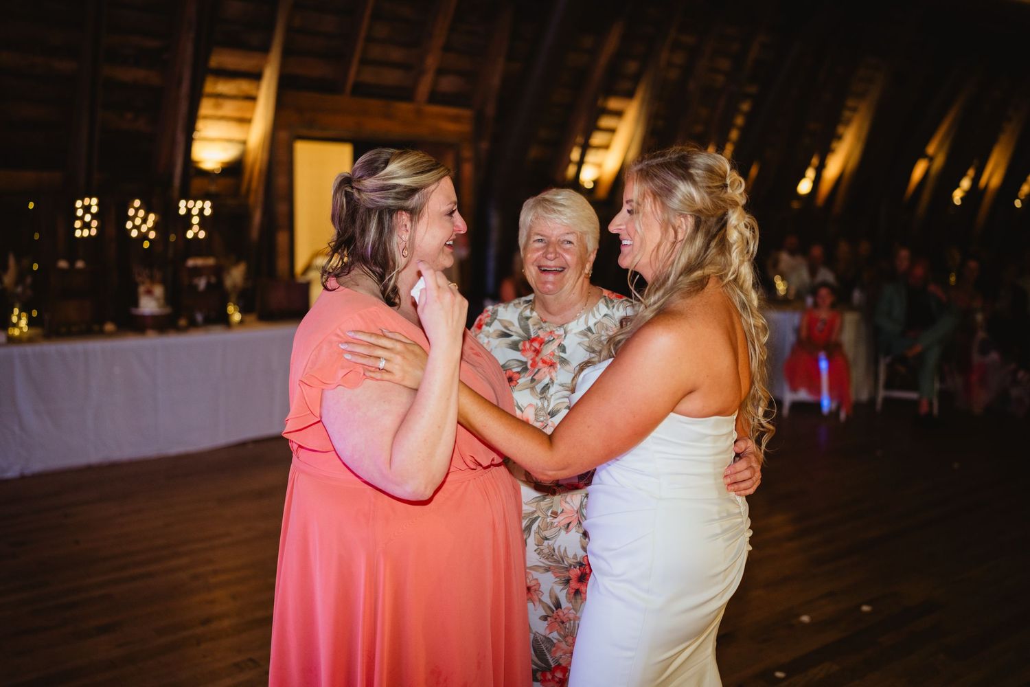 Three people are dancing together on a dimly lit dance floor at what appears to be an evening celebration or party.