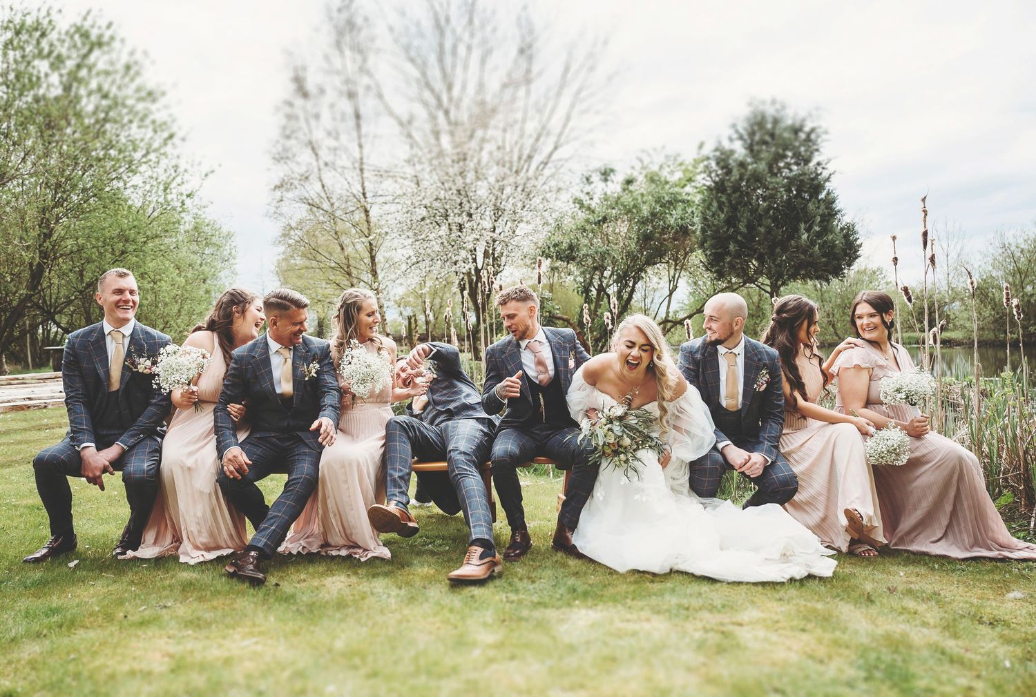 Wedding party in elegant dresses poses together on emerald green velvet couch during evening celebration.