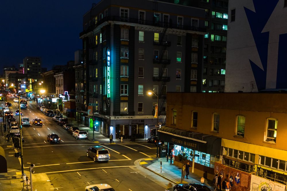Nighttime cityscape showing illuminated buildings and streets with a neon blue glow against a dark sky.